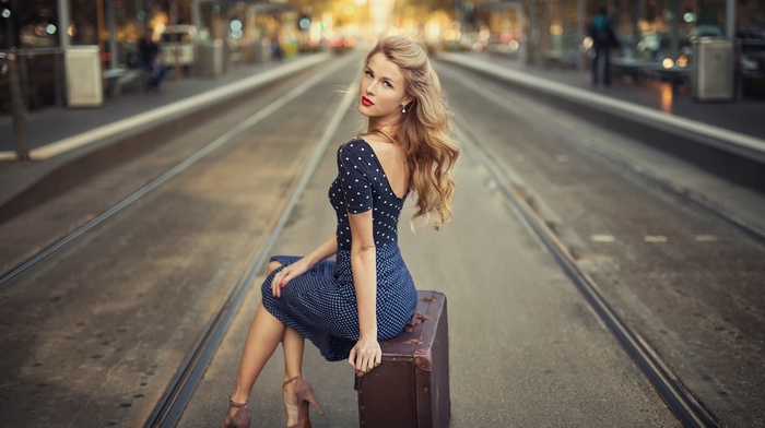 blue dress, blonde, looking at viewer, stiletto, sitting, high heels, model, street, long hair, girl outdoors, suitcases, rail yard, girl, polka dots, depth of field