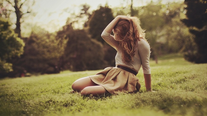 girl outdoors, grass, sitting, hands in hair, skirt, depth of field