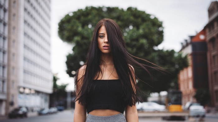 windy, face, girl outdoors, open mouth, Julia Carina, model, city, black tops, street, brunette, urban, depth of field, trees, girl, hair in face, long hair, portrait, looking at viewer, building
