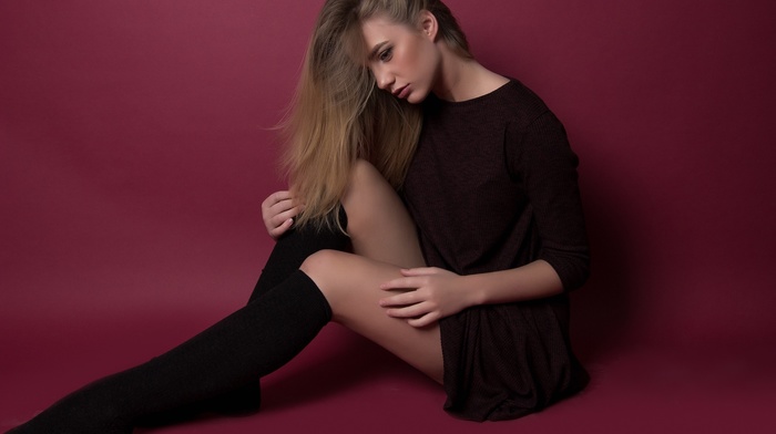 black stockings, blonde, girl, sitting, looking down, simple background