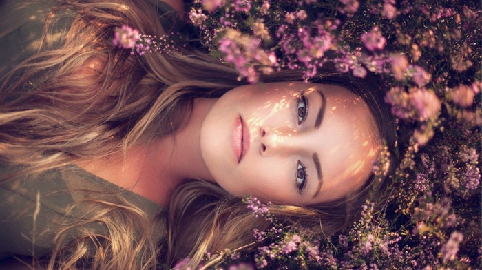 brown eyes, model, flowers, lying on back, girl, looking at viewer, face, depth of field, nature, portrait, girl outdoors, long hair, sunlight, blonde