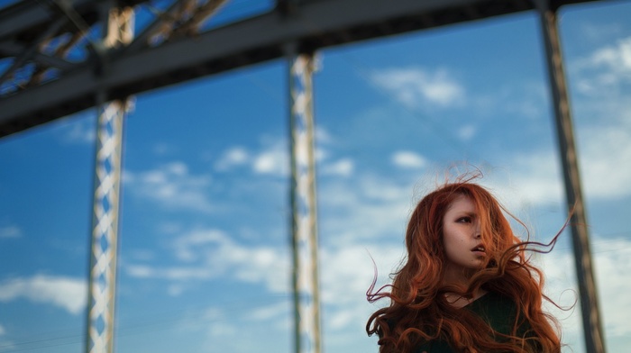 model, construction, clouds, girl outdoors, long hair, windy, open mouth, looking away, depth of field, hair in face, girl, redhead