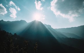 Mountain Range Illuminated By Sunlight Through Clouds