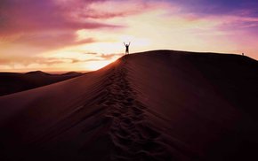 Man Standing On Sand Dune At Sunset