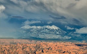 Snow-Capped Peaks Amidst Rocky Terrain And Clouds